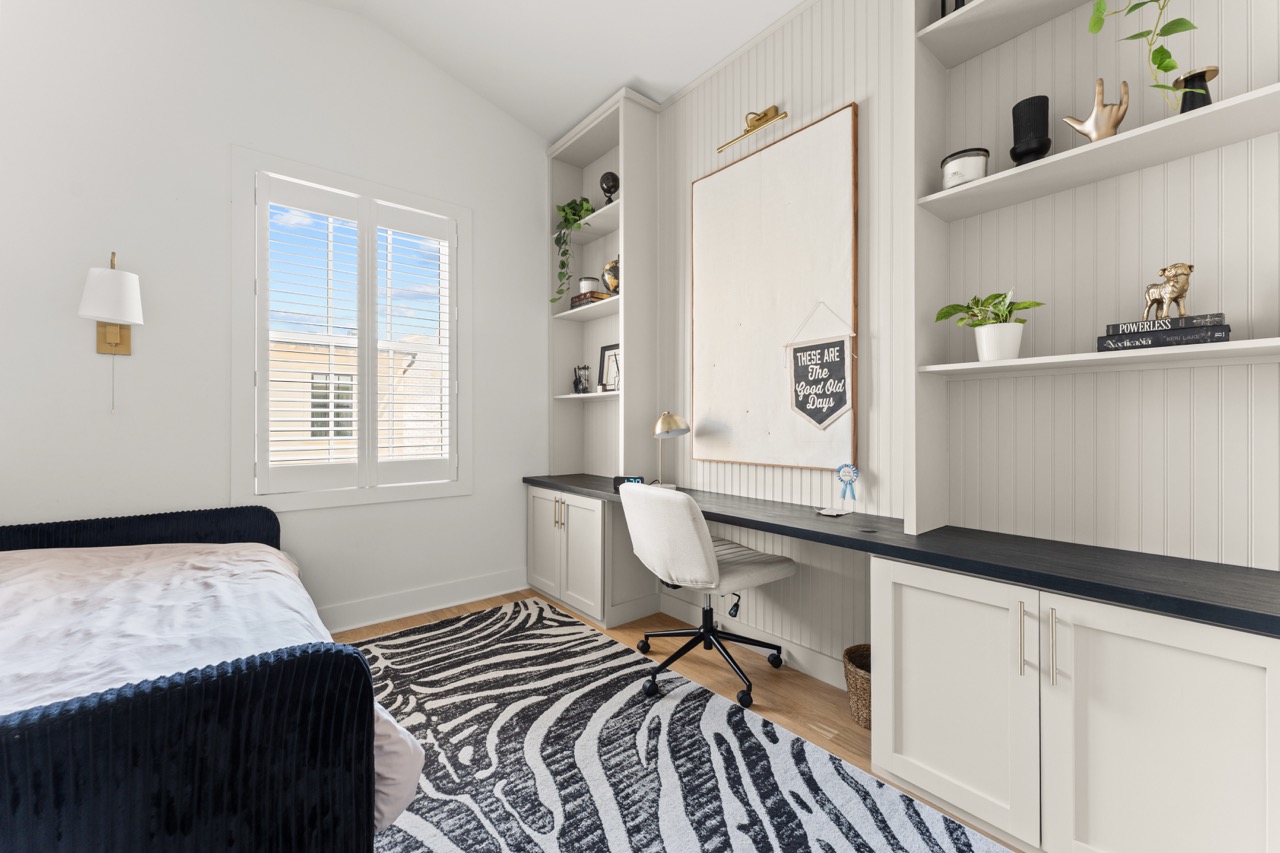 Bedroom with built-in desk, panelled shelving and open storage