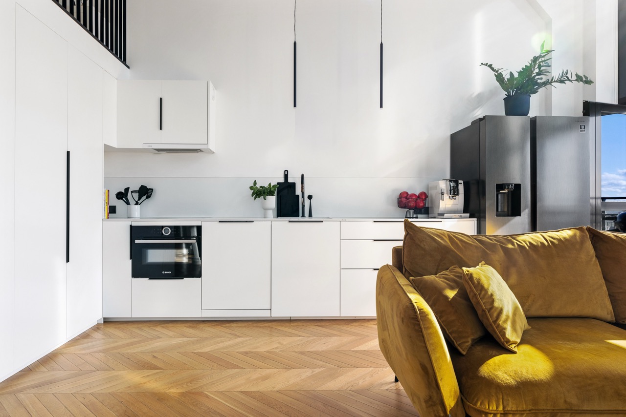 Loft kitchen with herringbone floors and ochre sofa